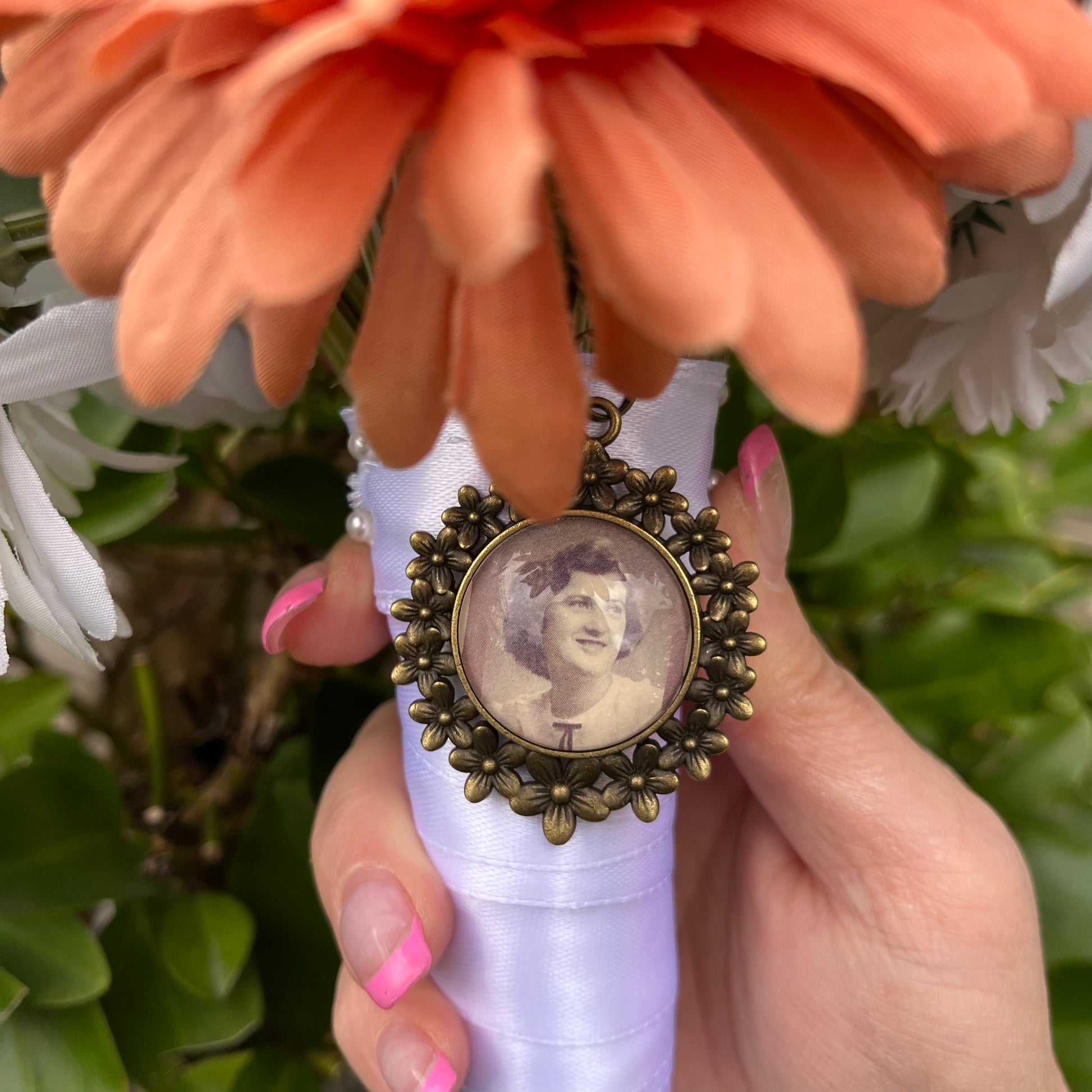 Bronze daisy pendant with a photo inside on a wedding flower arrangement. 