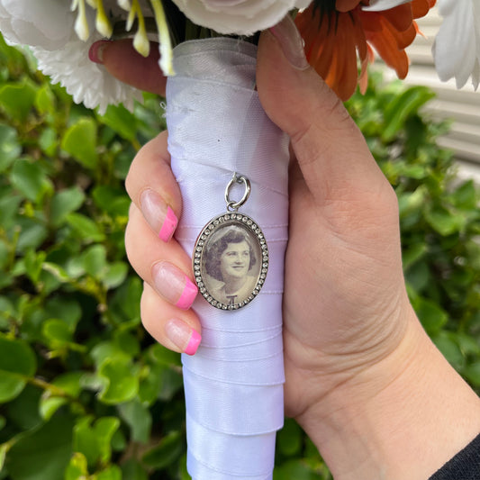 Oval diamante pendant with an image inside on a wedding bouquet.