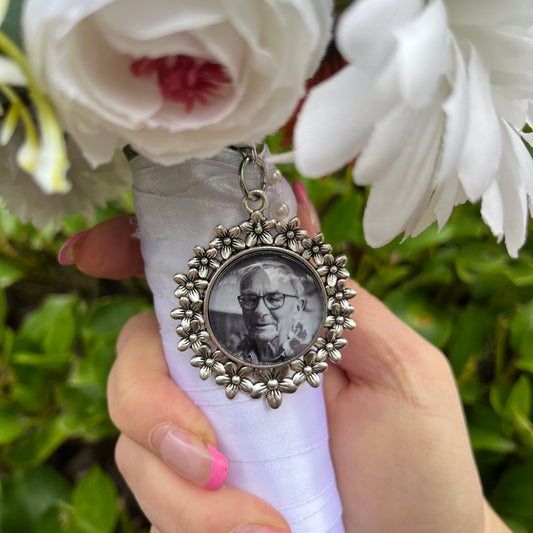 Silver daisy pendant with a photo inside it on a floral weddng bouquet 